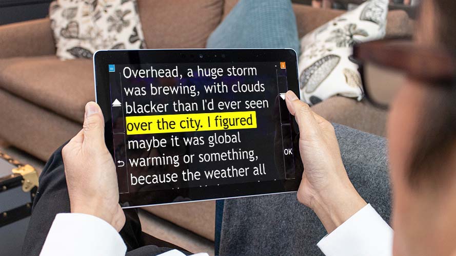 Holding a tablet using GuideConnect with large magnified text on screen.