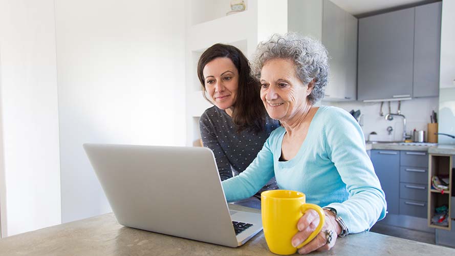 A woman and her mother looking at a laptop screen together.