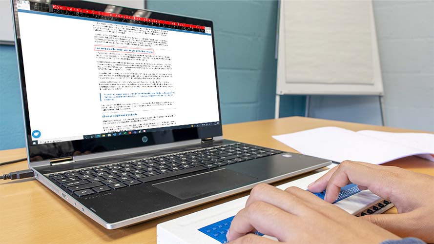 Braille reader connected to a Windows Laptop with words displayed on screen.