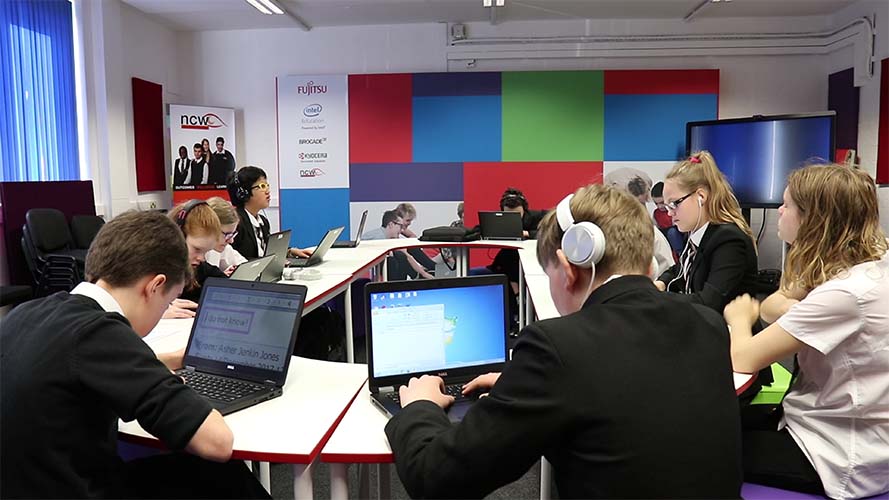 A group of children in a classroom using computers.