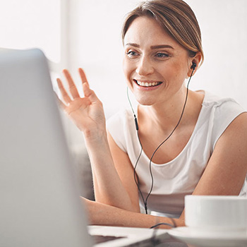 Happy woman watching a webinar on a laptop and waving at the screen